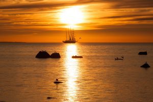 Old tall sail ship silhouette in sunset in sea