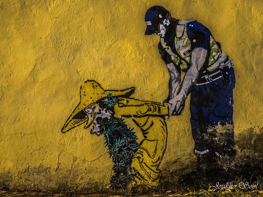 Keltainen seinä, jossa Edward von Lõngusin katutaideteos, joka kuvaa tontun näköisen hahmon pidättämistä